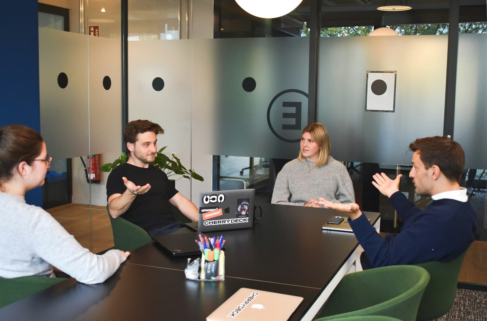 Four people in a meeting around a table in a modern office.